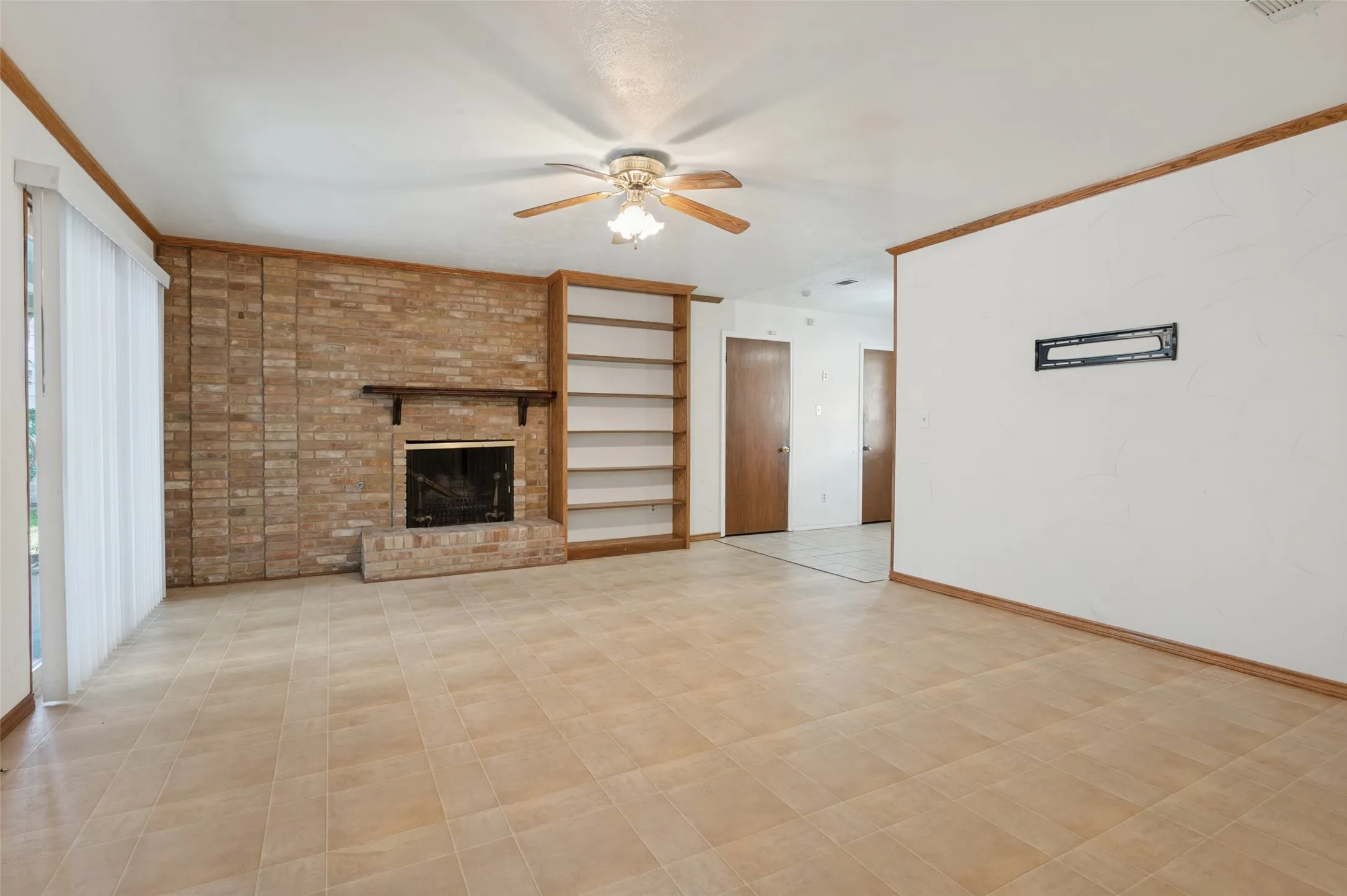 Brick fireplace with a dark wood mantel and built-in shelving