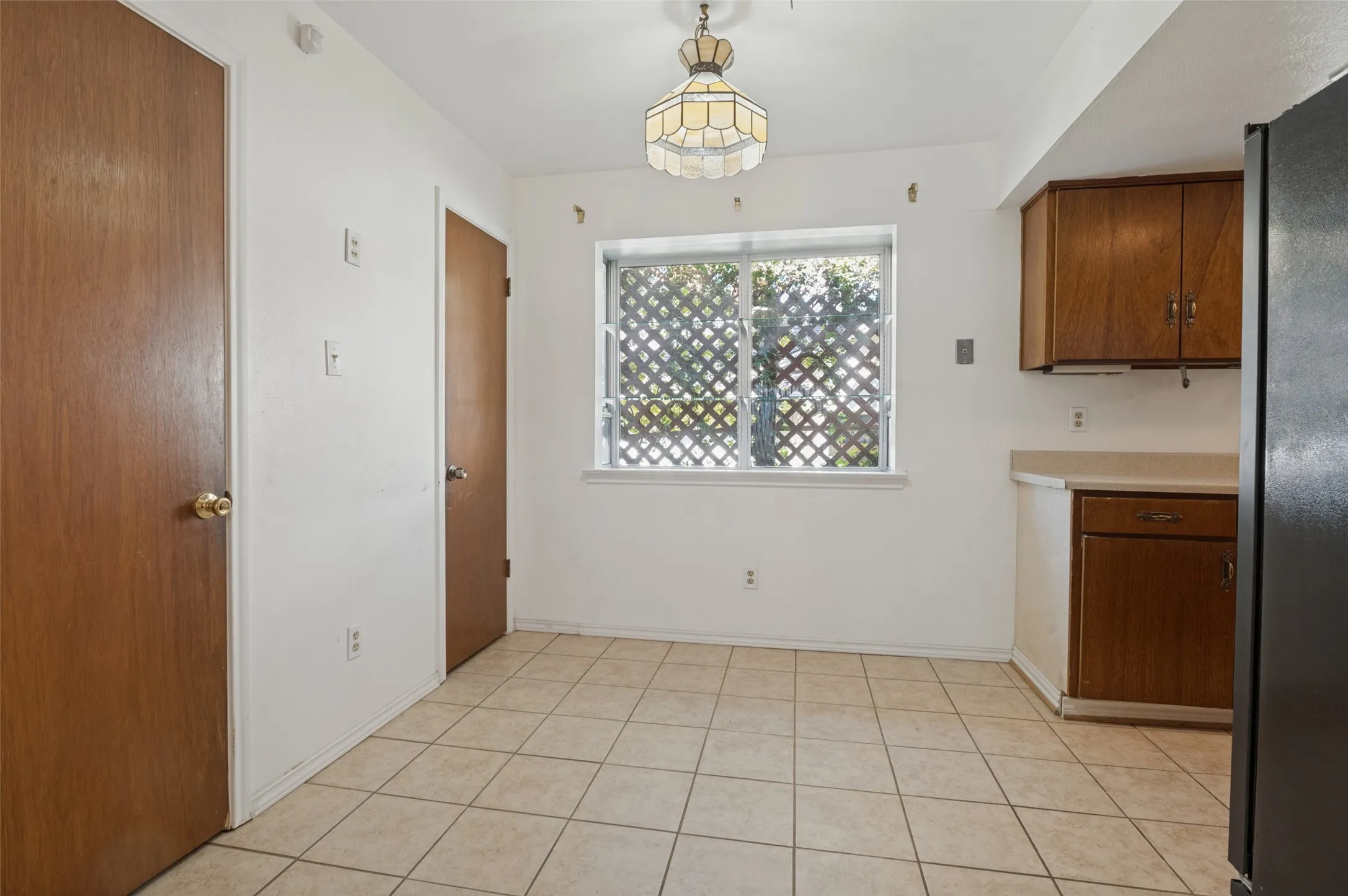 Tile flooring, wood-finish cabinetry, built-in overhead lighting, and a window with lattice detailing