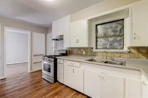 Kitchen featuring wood-finish flooring, white cabinetry, integrated stainless steel appliances, and a double basin sink