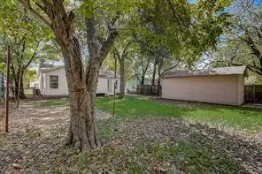 Expansive backyard featuring a large mature tree, a detached utility building, and a wood privacy fence
