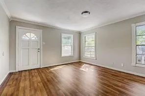 Wood-finish flooring, light gray walls, white trim, multiple windows, and a ceiling-mounted light fixture