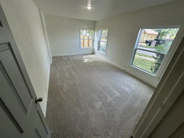 Carpeted room with multiple windows and a flush-mount ceiling light
