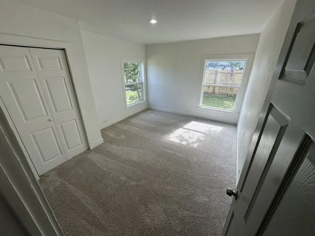 Neutral-toned carpeting with white walls, recessed ceiling lighting, and a bi-fold closet door