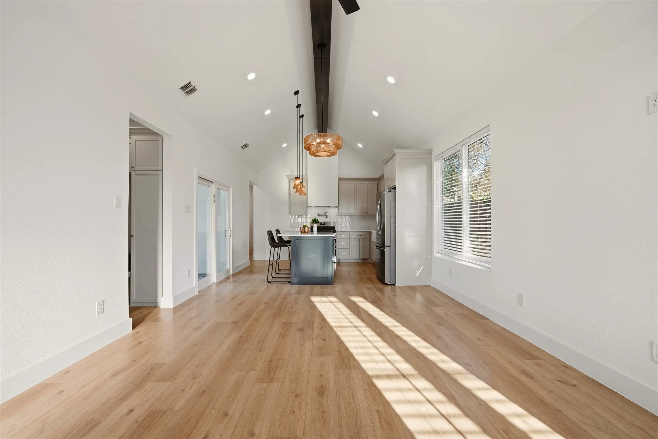 Vaulted ceiling, recessed lighting, wood-finish flooring, kitchen island, and stainless steel appliances