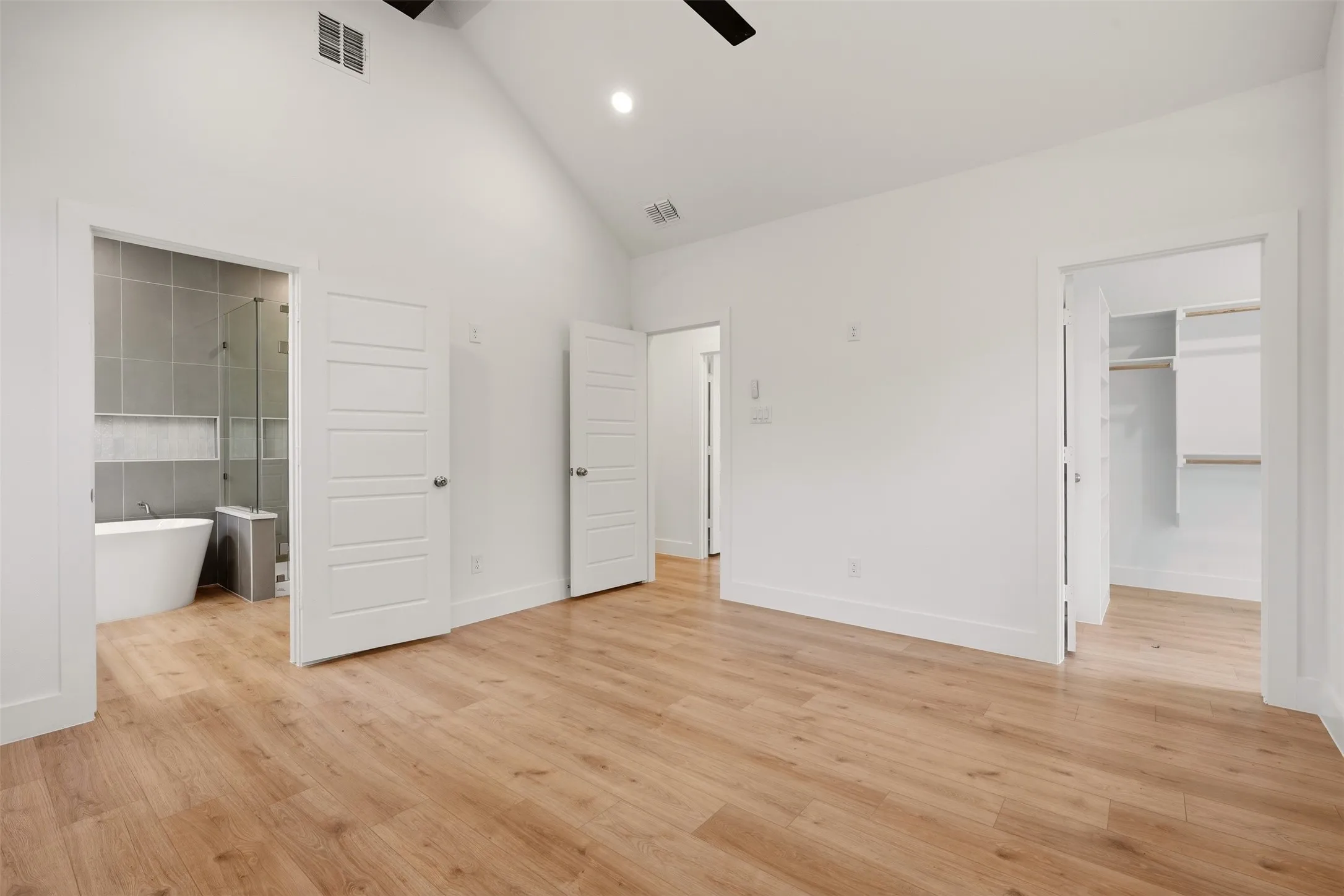 Vaulted ceiling, wood-finish flooring, white paneled doors, walk-in closet, freestanding soaking tub