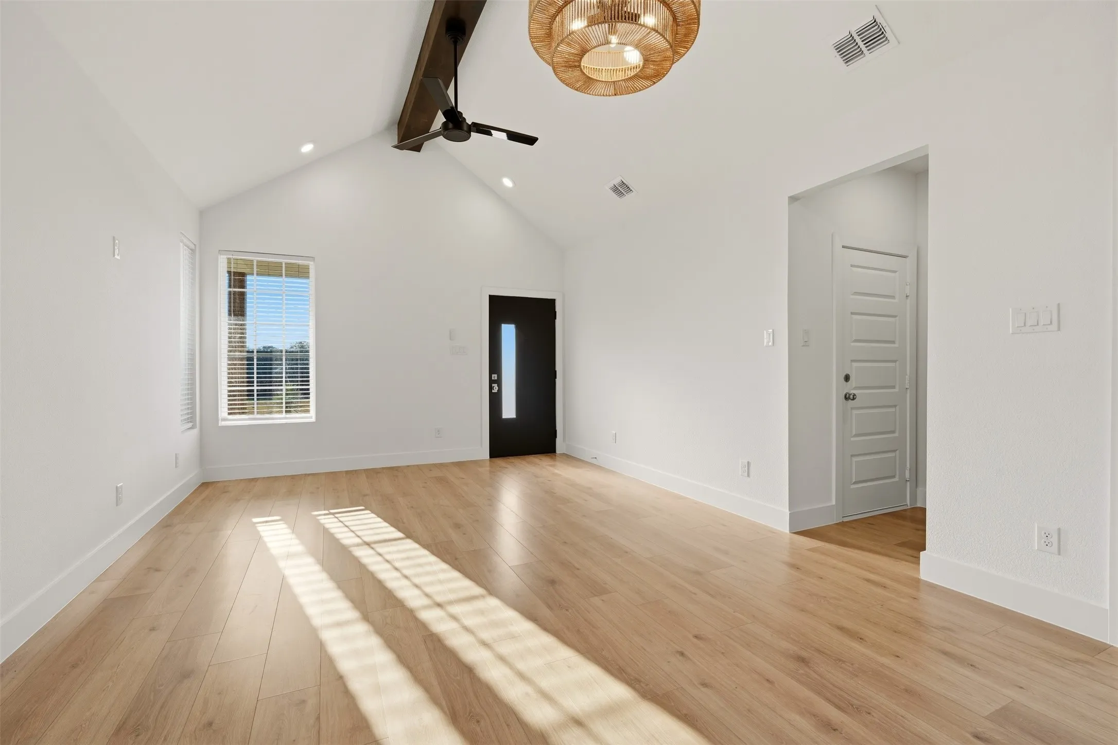 Vaulted ceilings, wood-finish flooring, and a decorative ceiling fan with an exposed beam