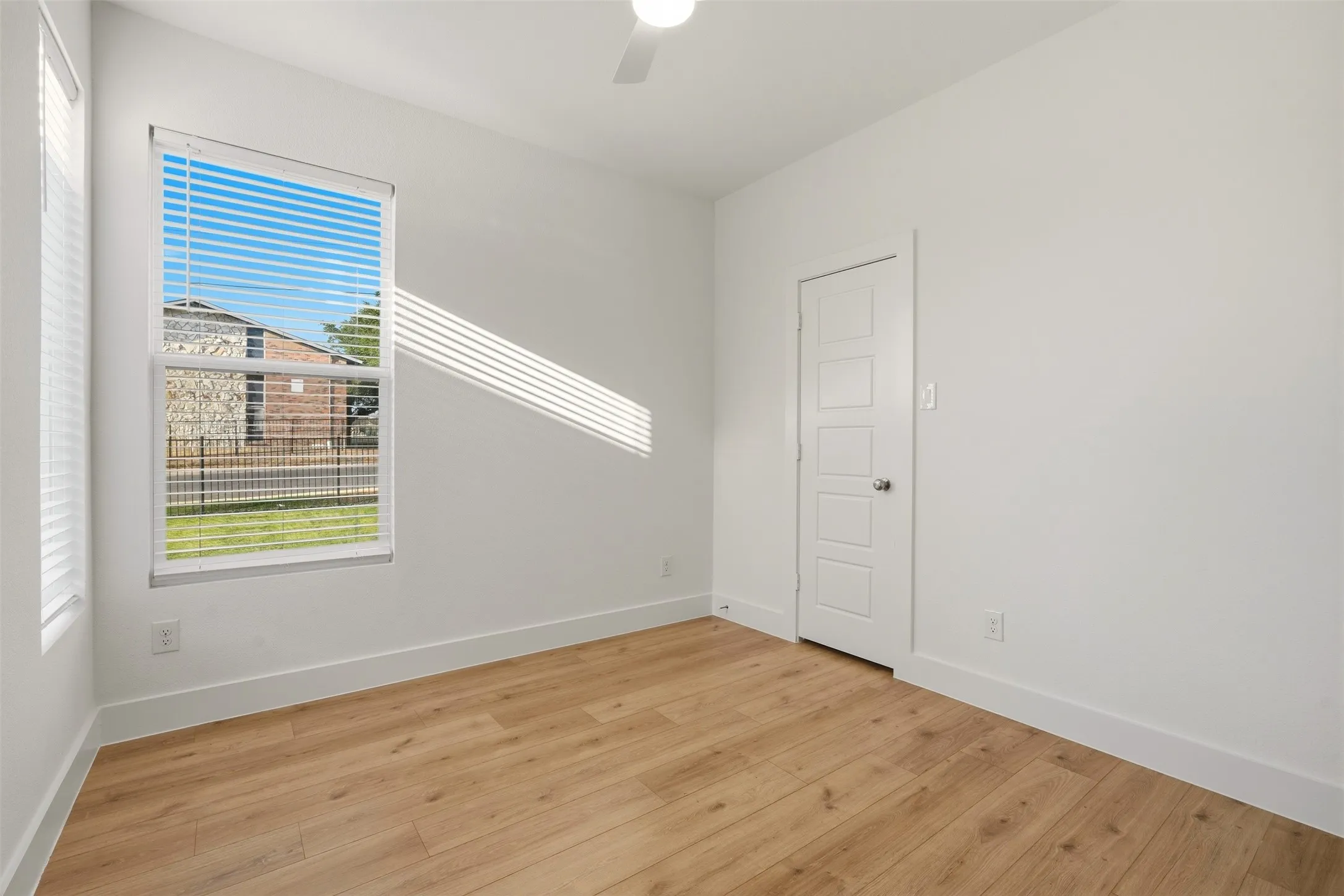 Bright room featuring wood-finish flooring, white walls, and a multi-paneled door