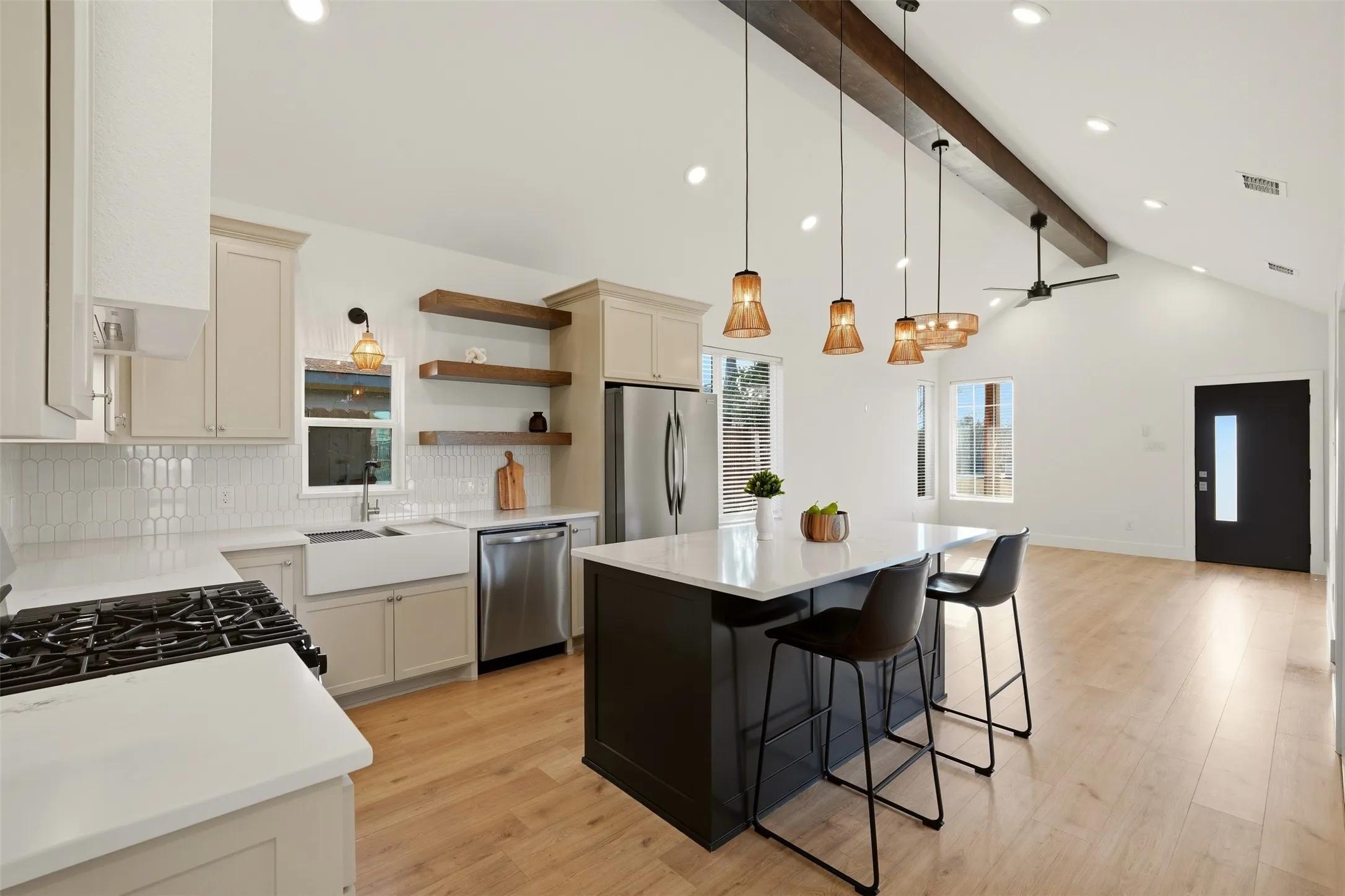 Open-concept kitchen with vaulted ceilings, recessed lighting, wood-finish flooring, a kitchen island, and a stainless steel refrigerator