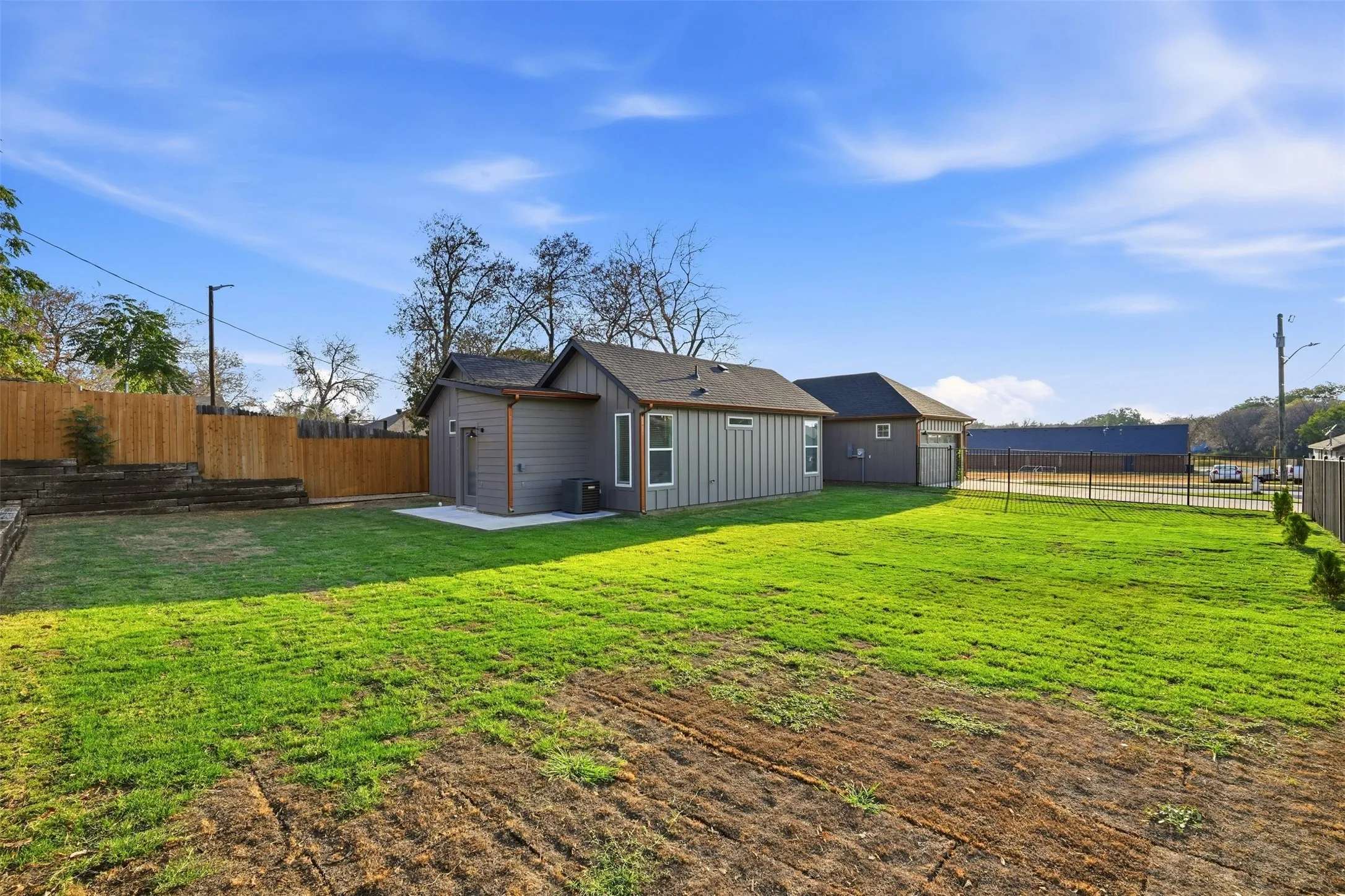 Expansive rear yard featuring green lawn, privacy fencing, a concrete patio, and a detached structure