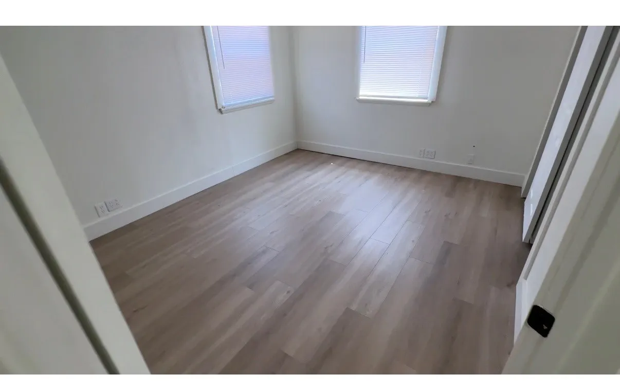 Wood-finish flooring, white walls, and two windows with blinds
