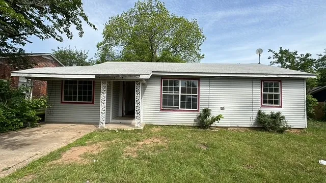 Light-colored siding exterior with a covered entry, white window frames with red trim, and a shingle roof