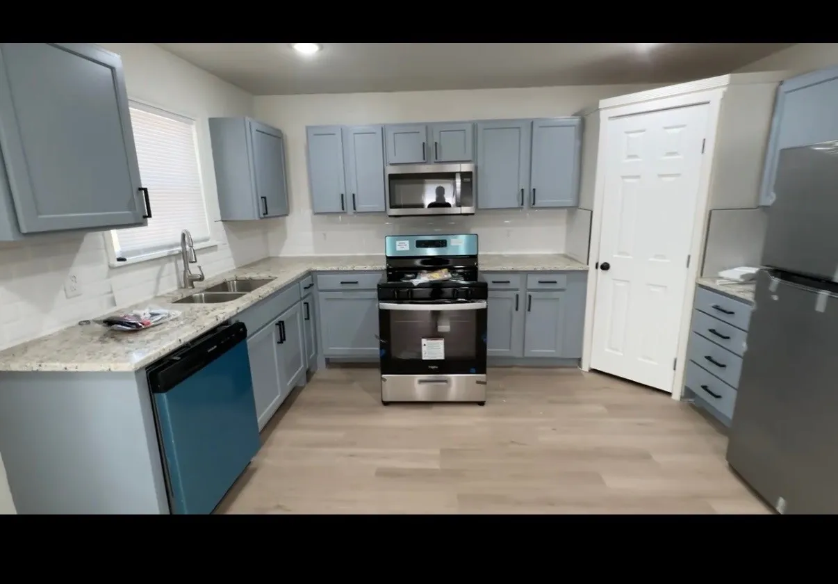 Kitchen featuring light grey cabinetry, light-toned countertops, a stainless steel sink, a stainless steel range, and wood-finish flooring