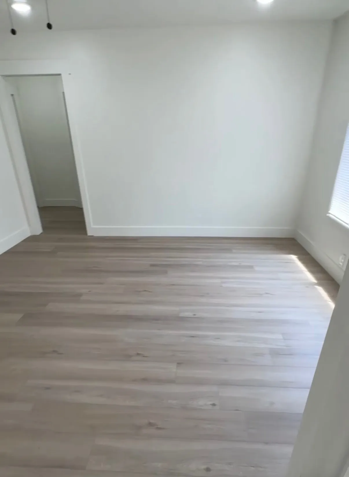 Light wood-finish flooring with white baseboards and walls
