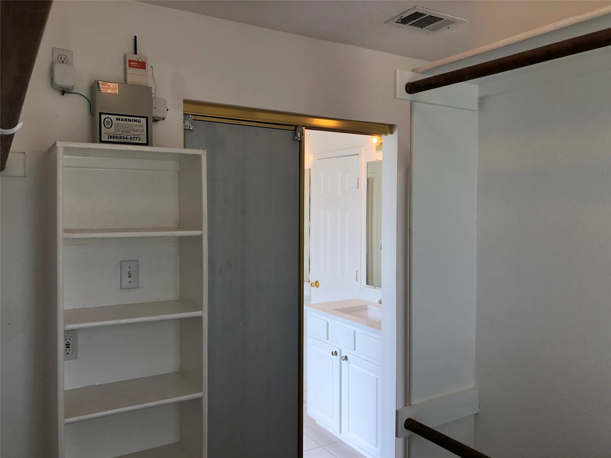 Built-in shelving, barn door entry, wall-mounted vanity, under-sink cabinetry, and integrated mirror