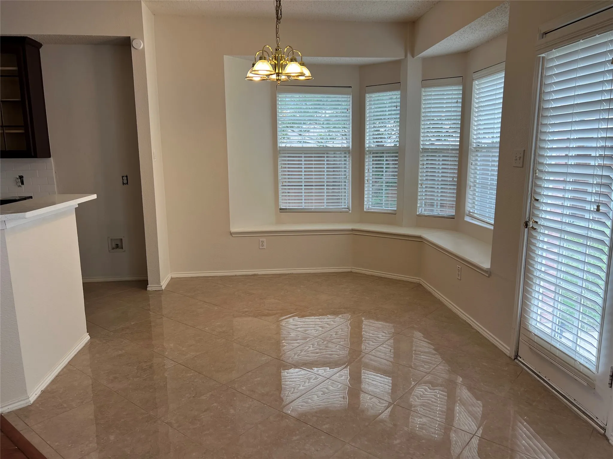 Recessed bay windows with an integrated window seat, pendant lighting fixture, tiled flooring, and a glass-paneled exterior door