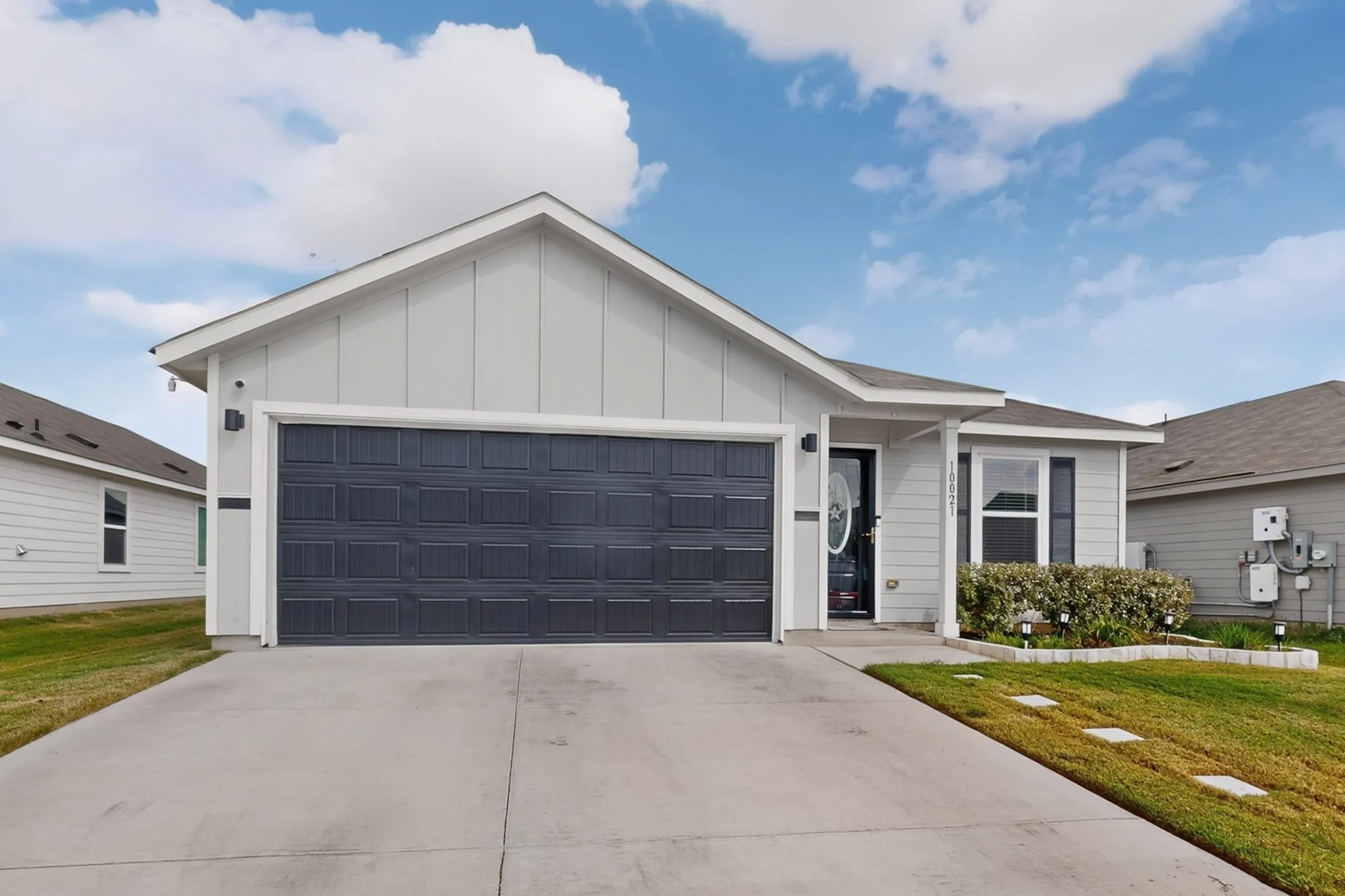 Single-story exterior with light gray siding and a dark gray paneled garage door