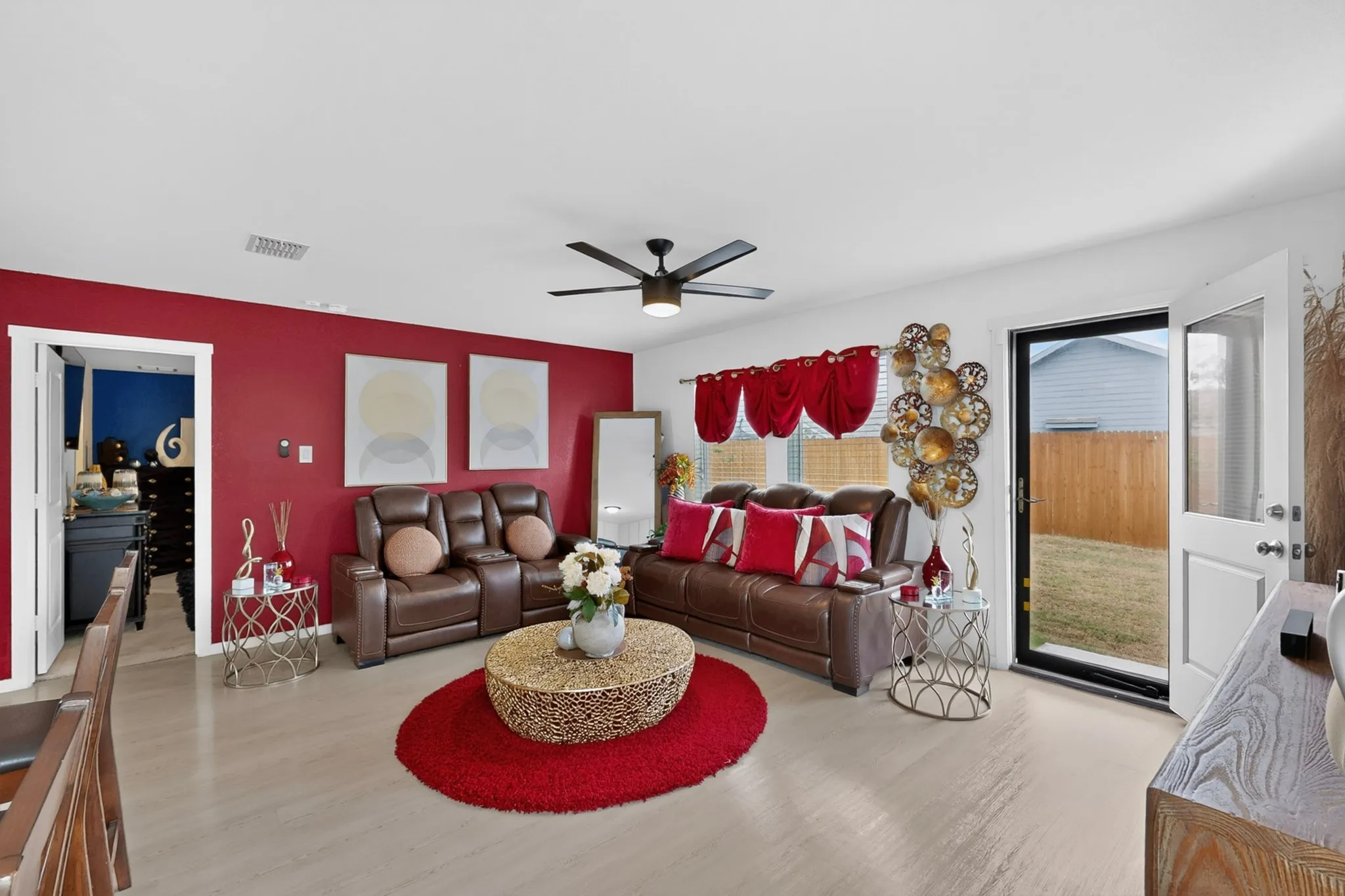 Wood-finish flooring throughout, featuring a modern ceiling fan with integrated lighting and a glass-paneled exterior door