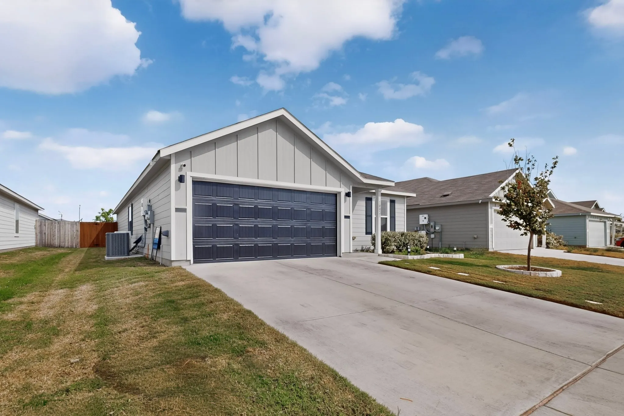 Contemporary exterior with light gray siding, a dark gray garage door, and a concrete driveway