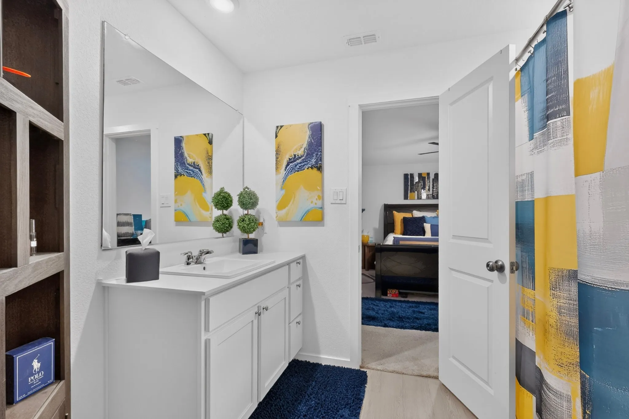 Vanity with an integrated sink and chrome faucet, large wall mirror, and wood-finish flooring
