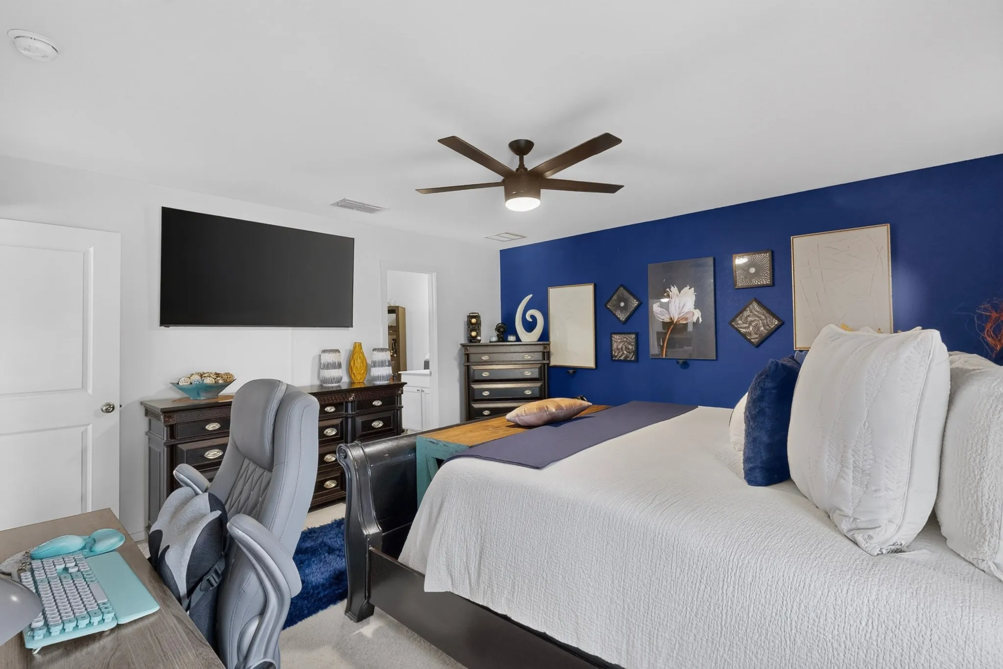 White walls with a bold accent wall, ceiling fan, and wood-finish flooring