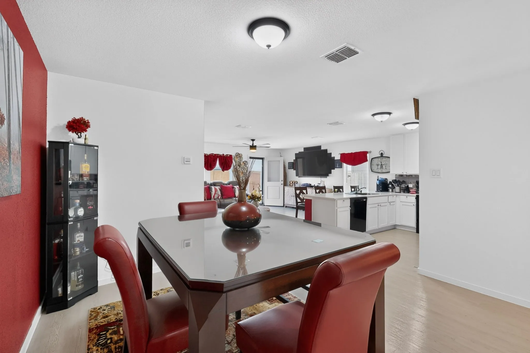 Light wood-finish flooring, recessed ceiling lighting, and white cabinetry with a black appliance suite
