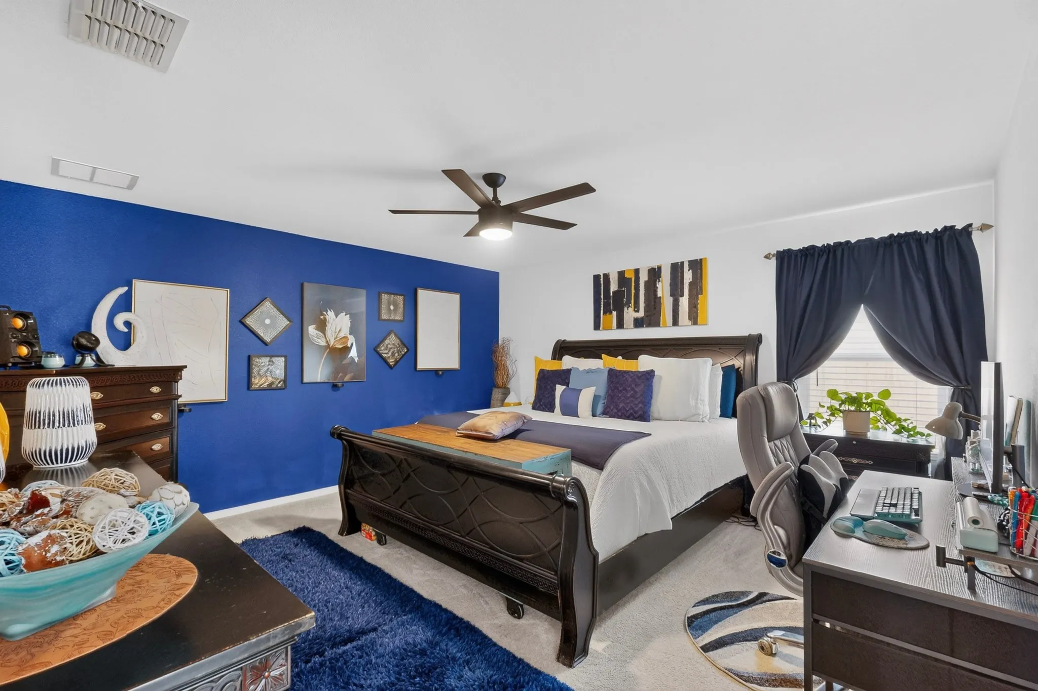 Spacious room featuring a ceiling fan, light gray carpeting, and a window with dark curtains