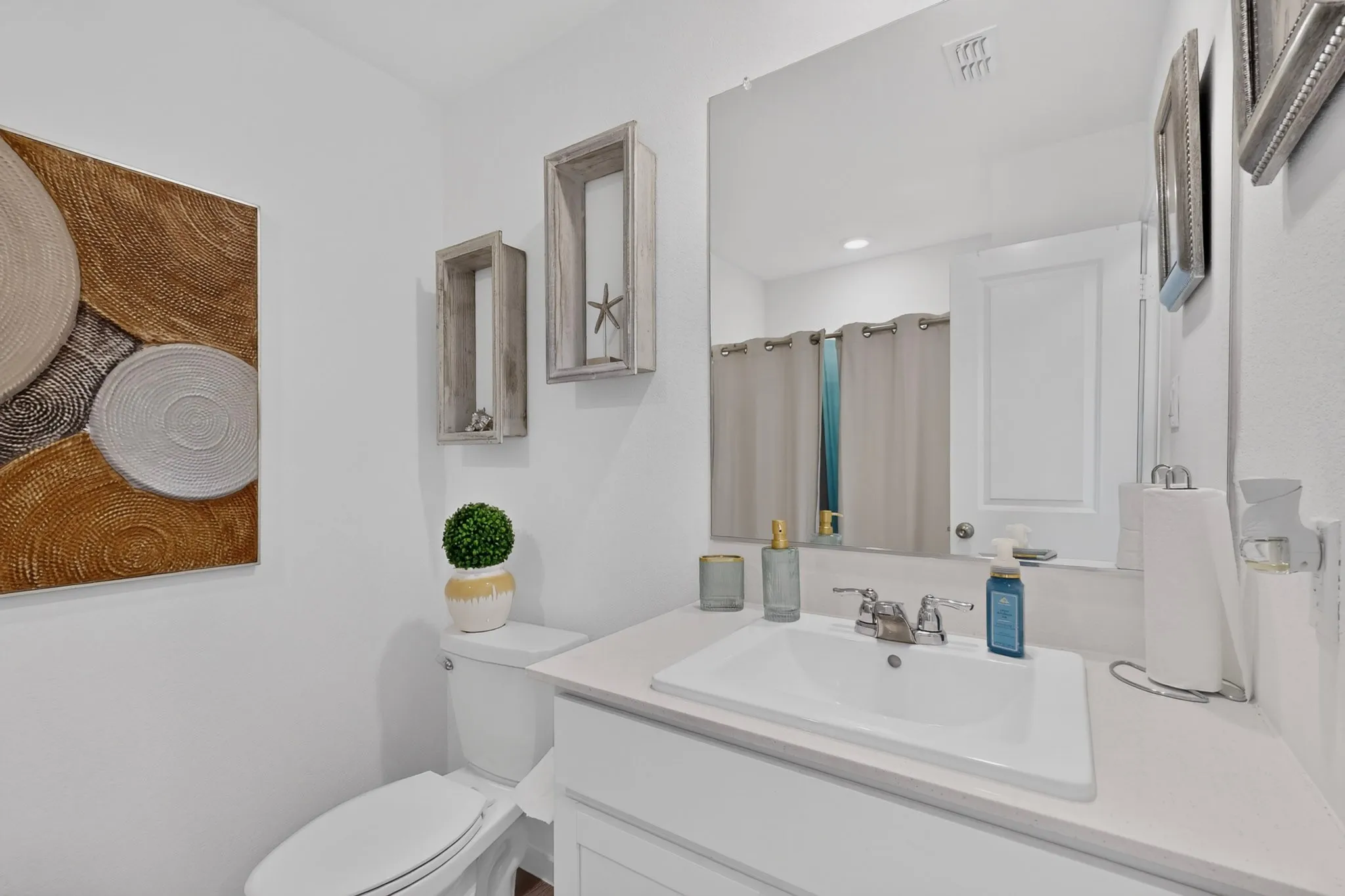 White vanity with integrated sink, chrome faucet, and expansive wall mirror