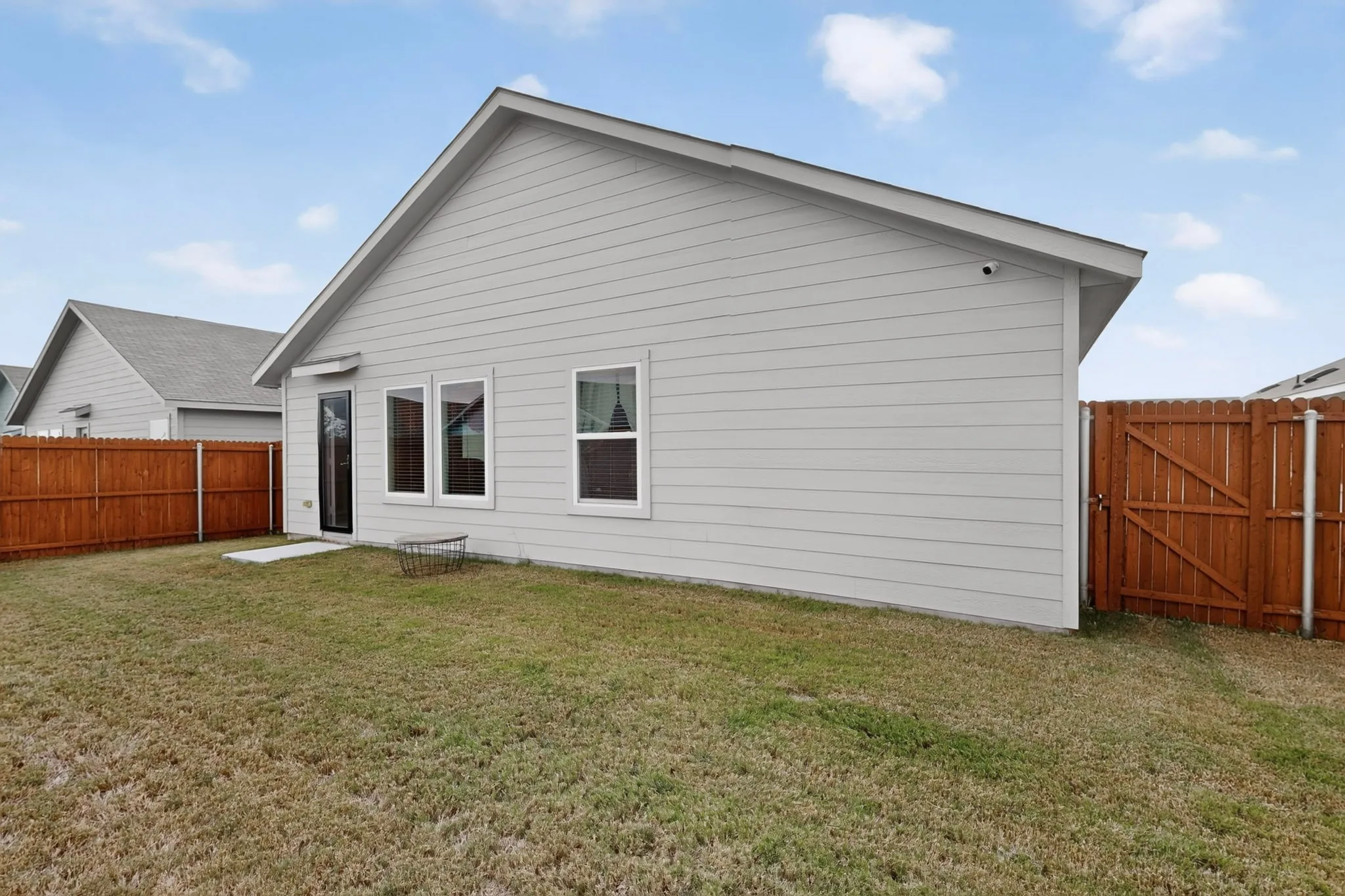 Expansive backyard featuring a wood privacy fence, a wood gate, and a concrete patio