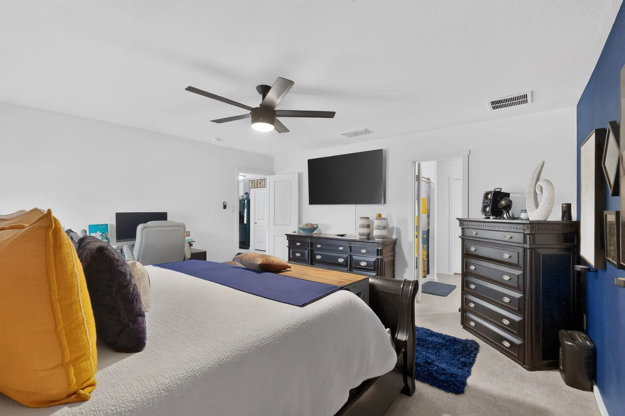 White painted walls with a feature wall, ceiling fan with integrated lighting, and carpeted flooring