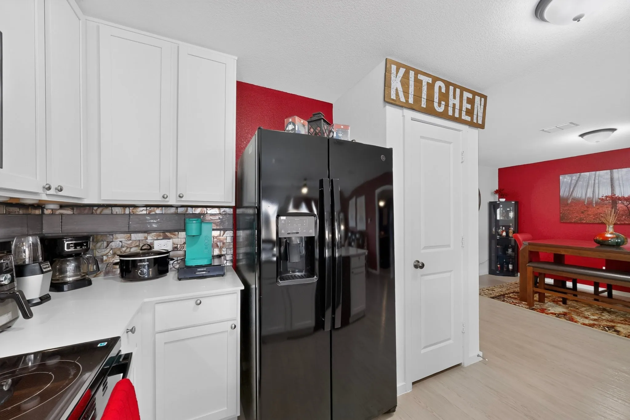 White shaker cabinetry with nickel hardware, solid surface countertops, and a tile backsplash