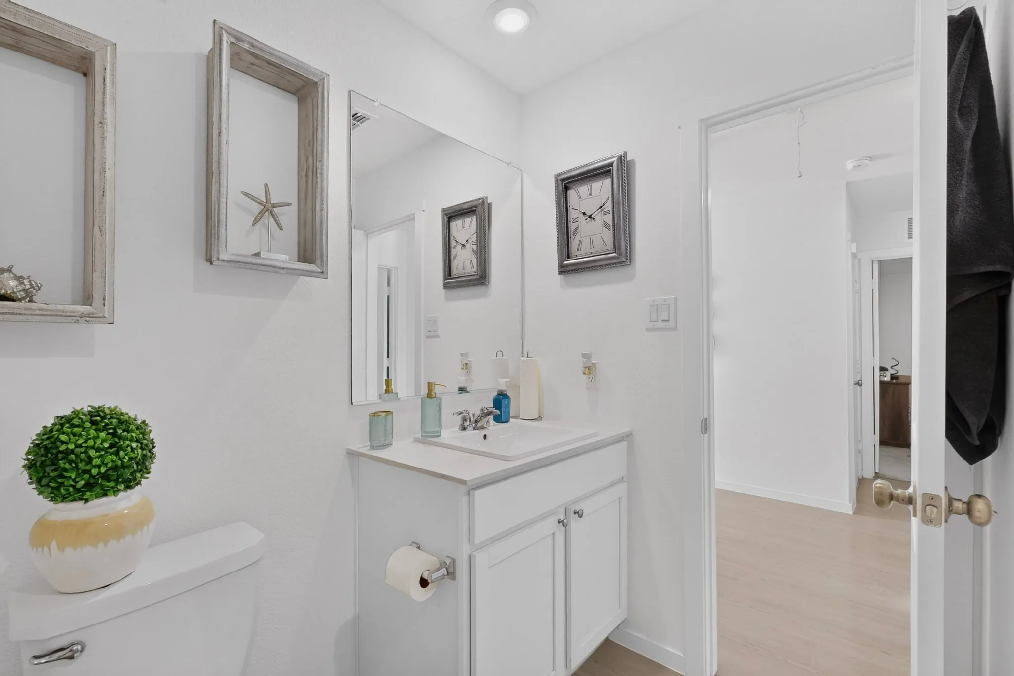 White vanity with cabinet storage, integrated sink, and wall-mounted mirror