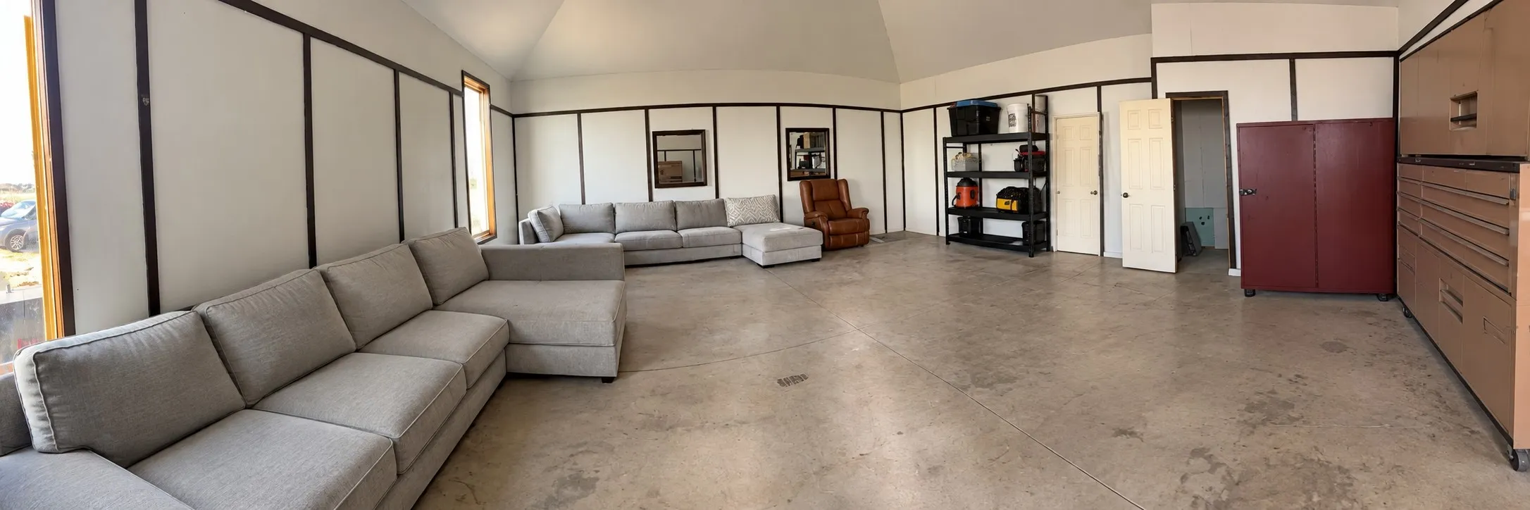 Vaulted ceiling, concrete flooring, and windows with wood-finish trim