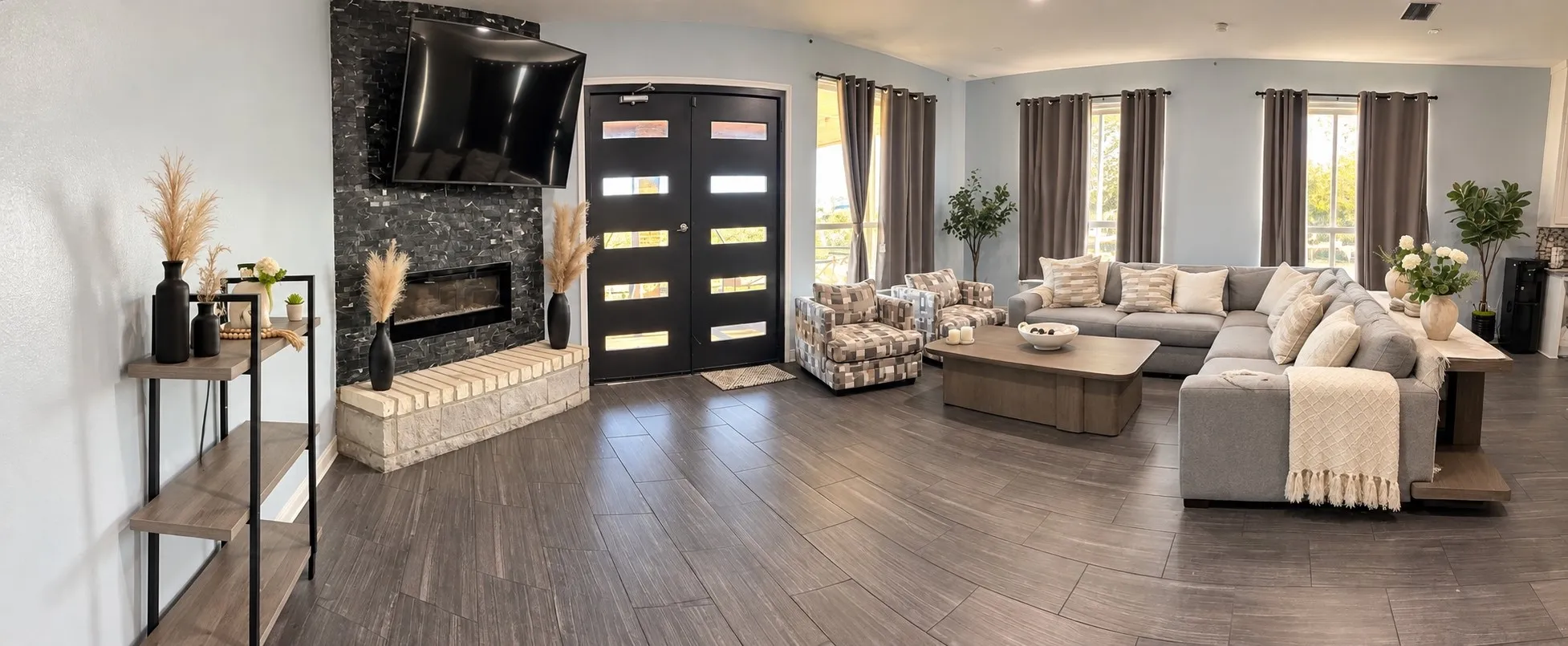 Wood-finish flooring throughout, featuring a fireplace with a stone-tile surround, and dual entry doors with frosted glass panels