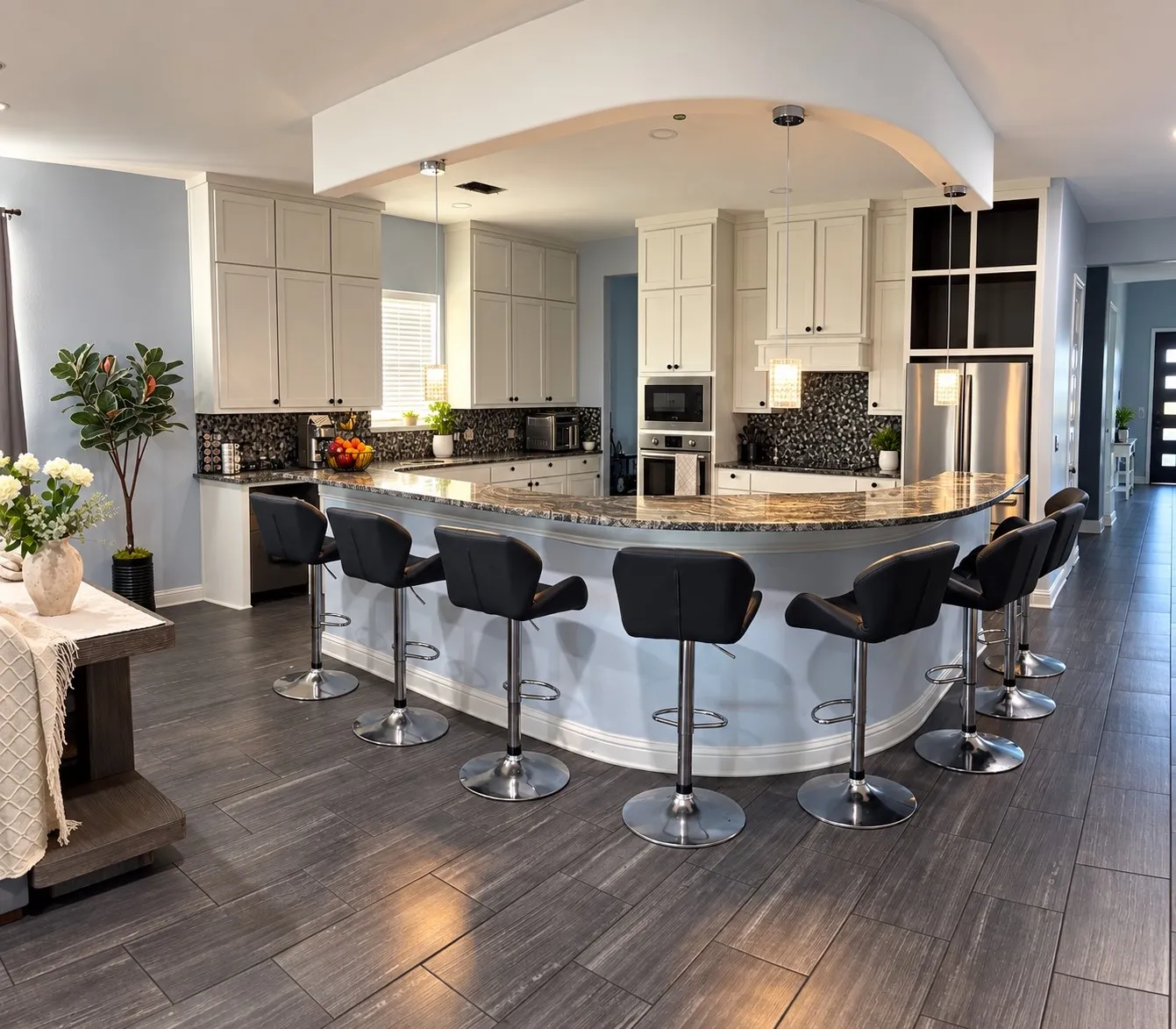Curved kitchen island with a stone countertop, integrated stainless steel appliances, white cabinetry, and a dark tile backsplash