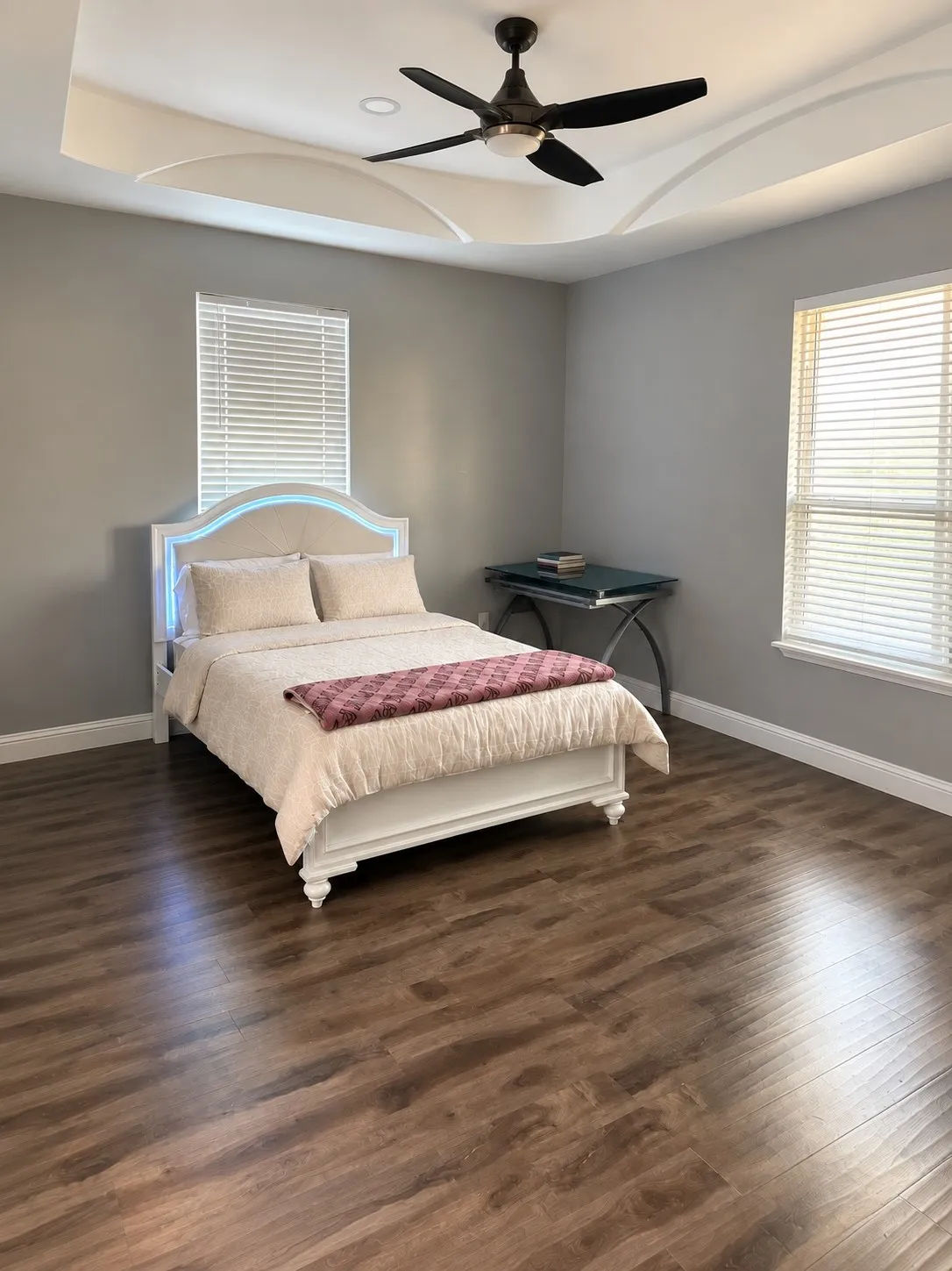 Wood-finish flooring throughout, tray ceiling with recessed lighting and a ceiling fan, and window blinds