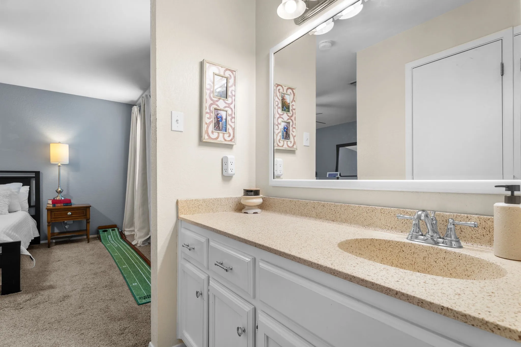 Bathroom vanity with a speckled countertop, undermount sink, dual-handle faucet, and white cabinetry