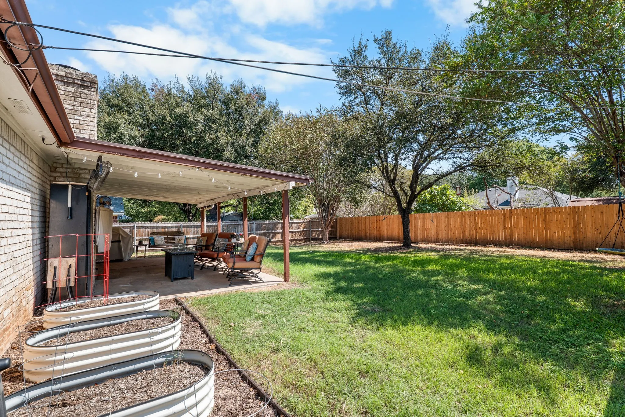 Expansive backyard featuring a covered patio, manicured lawn, and privacy fencing