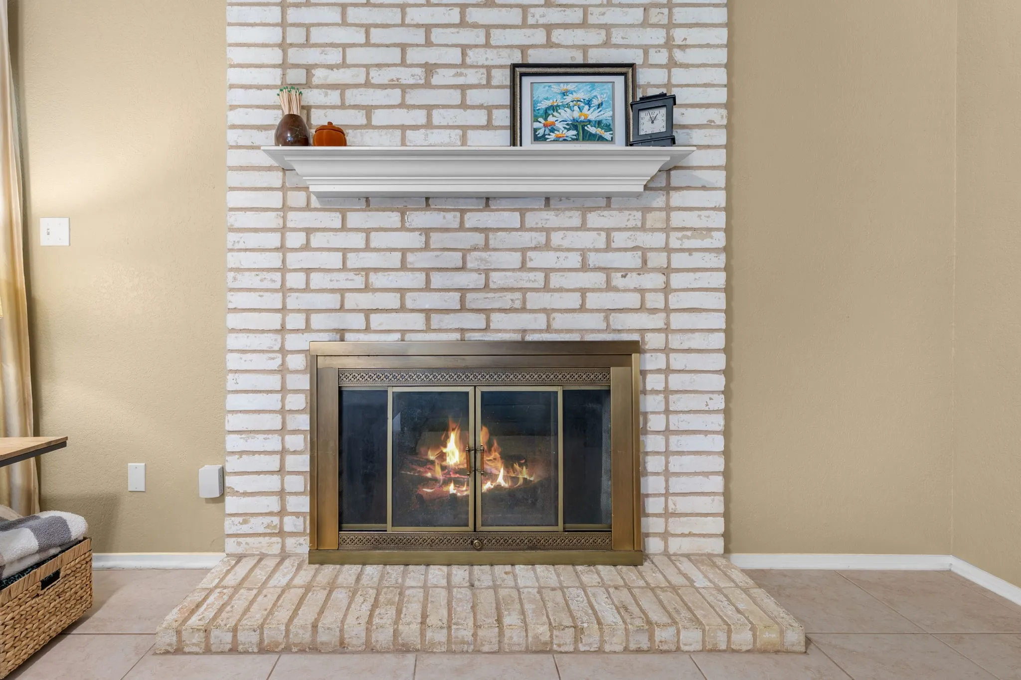 Brick fireplace with a painted finish and a brass-framed firebox