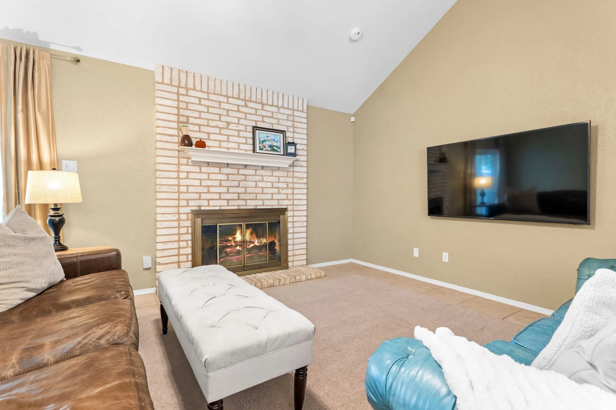 Vaulted ceiling with an exposed beam, brick fireplace, and built-in mantel