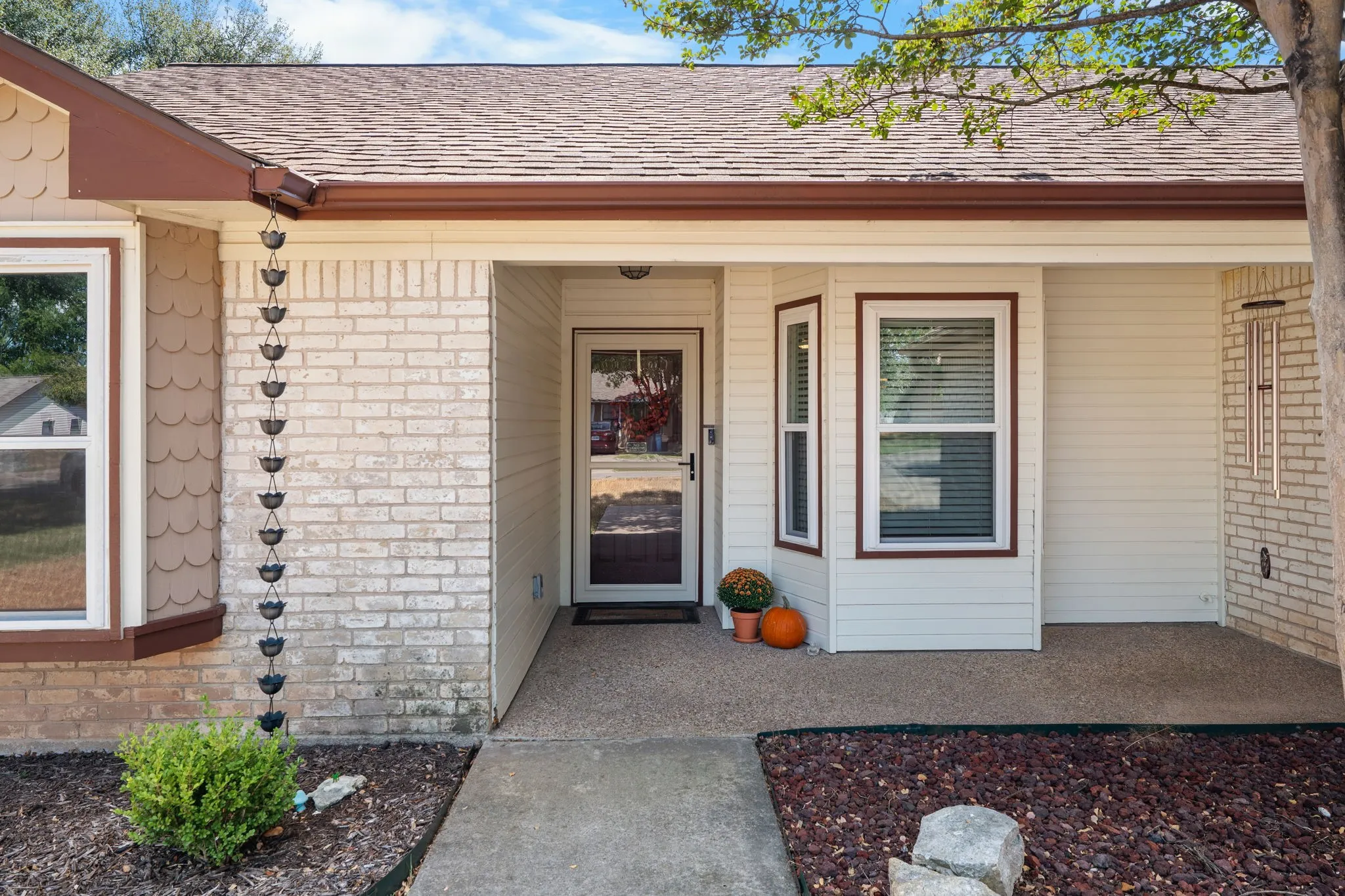 Brick and siding exterior with a covered entry, decorative rain chain, and bay window