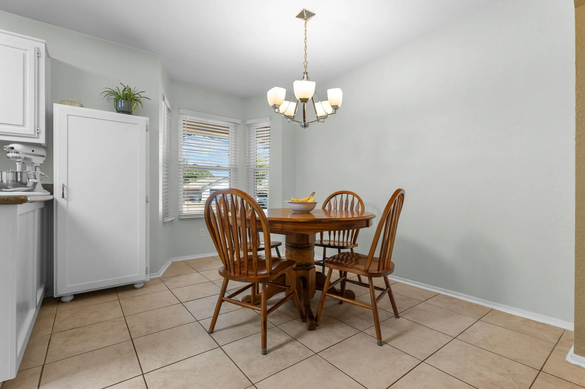 Light-toned tile flooring, bay window with blinds, and recessed lighting