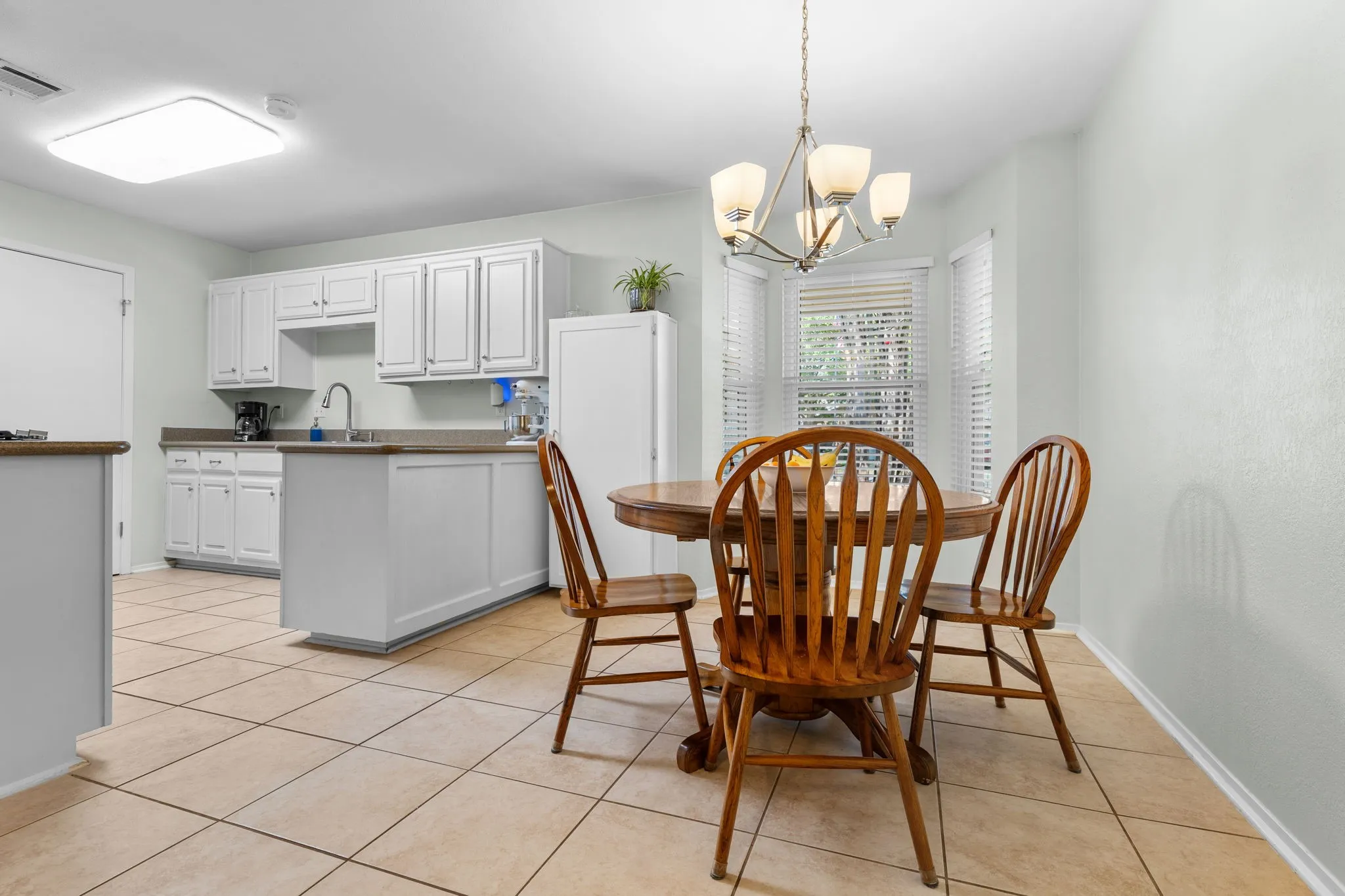 Tile flooring throughout, white cabinetry with a coordinating island, and a bay window