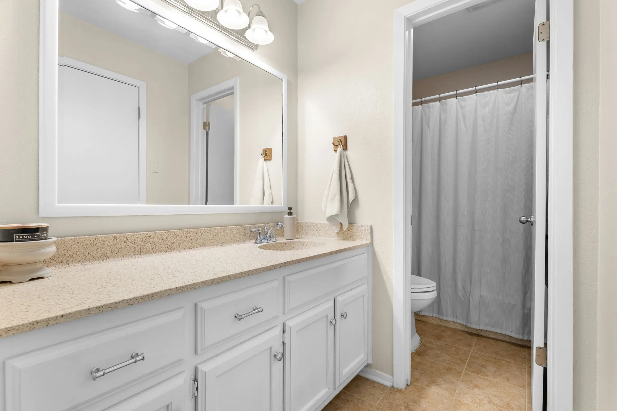 White vanity with chrome hardware, an integrated sink, and a light-toned countertop