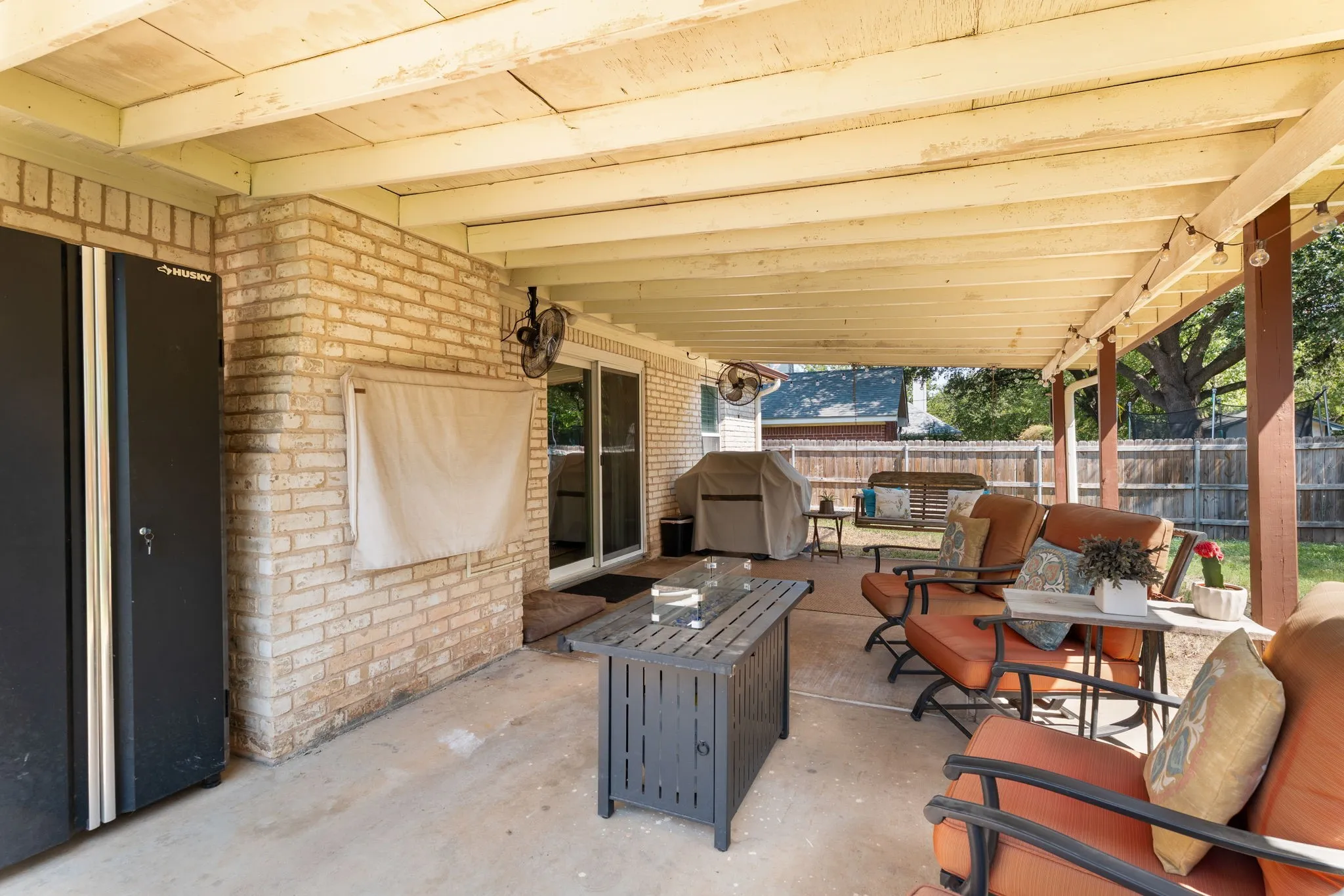 Covered patio with a concrete slab, exposed wood beam ceiling, and brick exterior wall