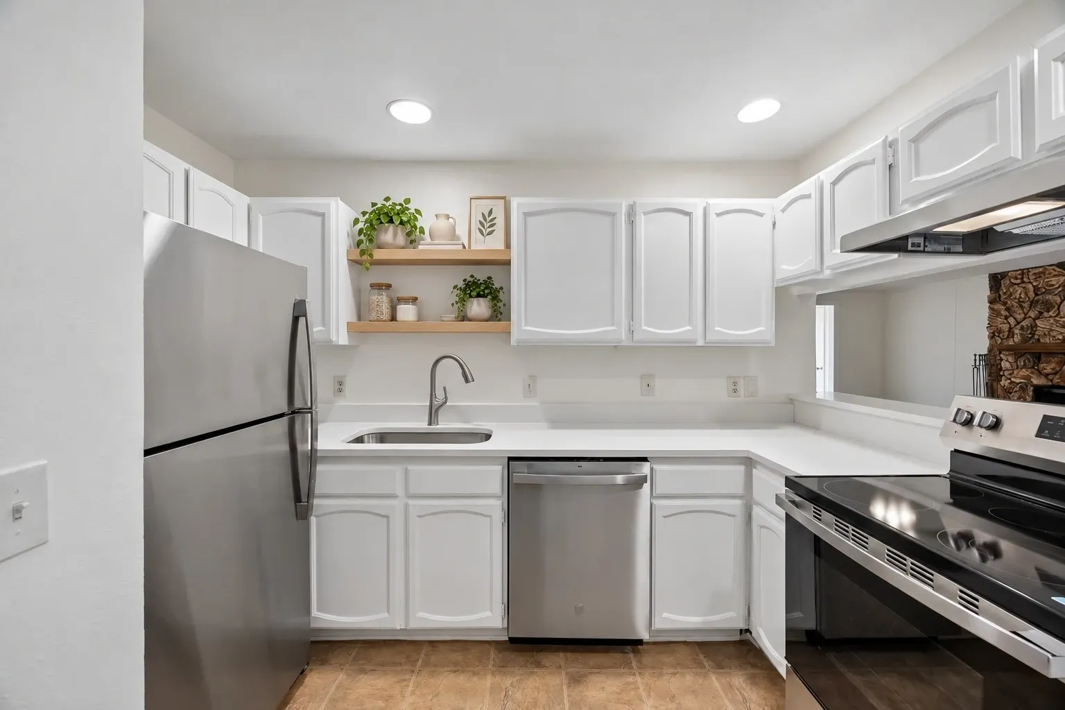White cabinetry with arch-panel doors, stainless steel appliances, and light-toned countertops