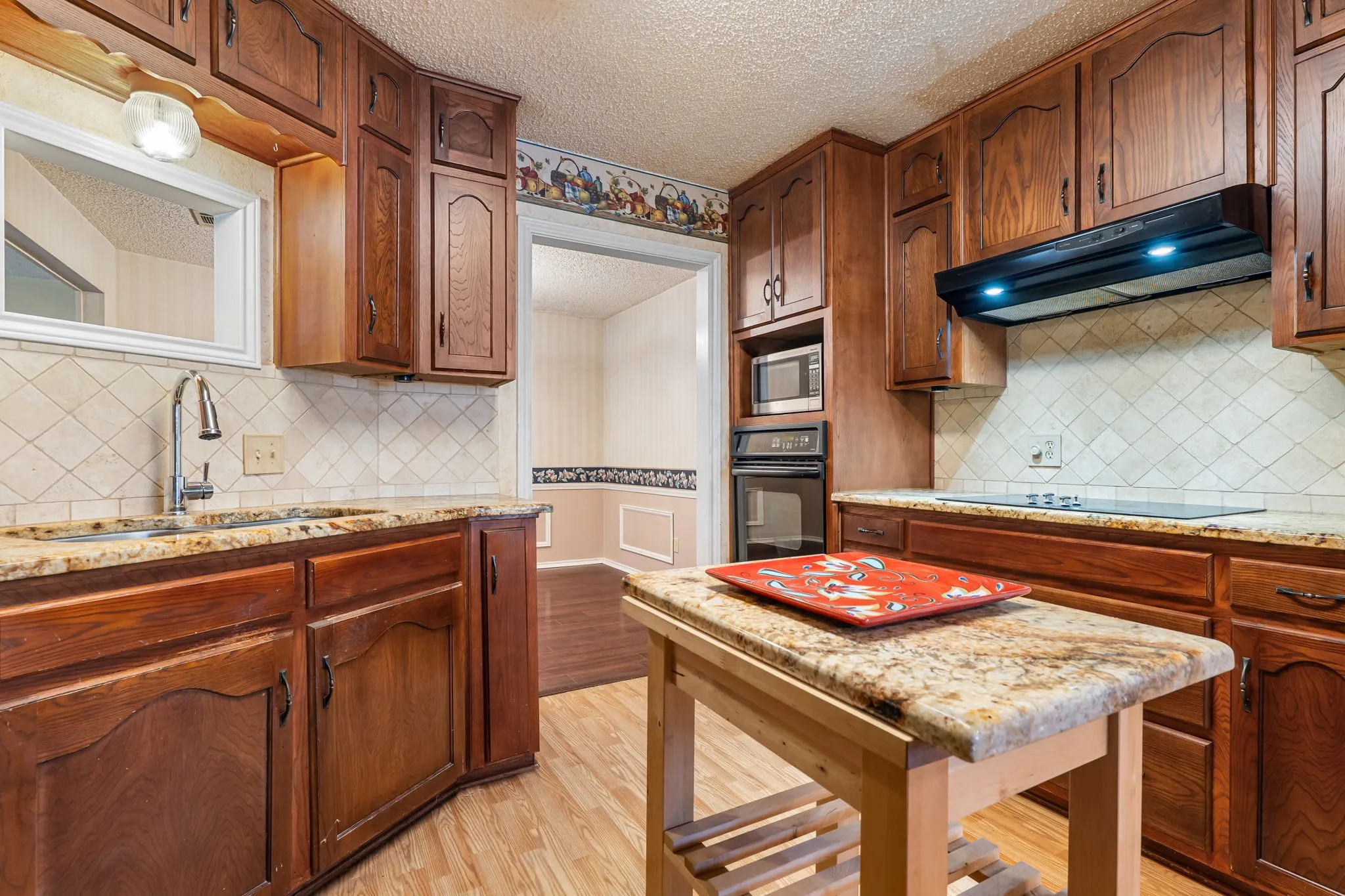 Kitchen featuring wood-finish cabinetry, granite countertops, tile backsplash, built-in microwave, and built-in oven