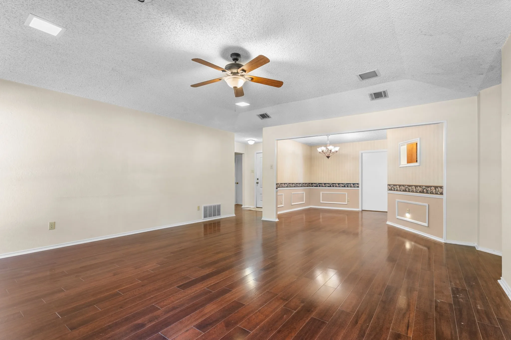 Wood-finish flooring throughout, ceiling fan with integrated lighting, recessed lighting, and an archway opening to an additional room with decorative wall paneling
