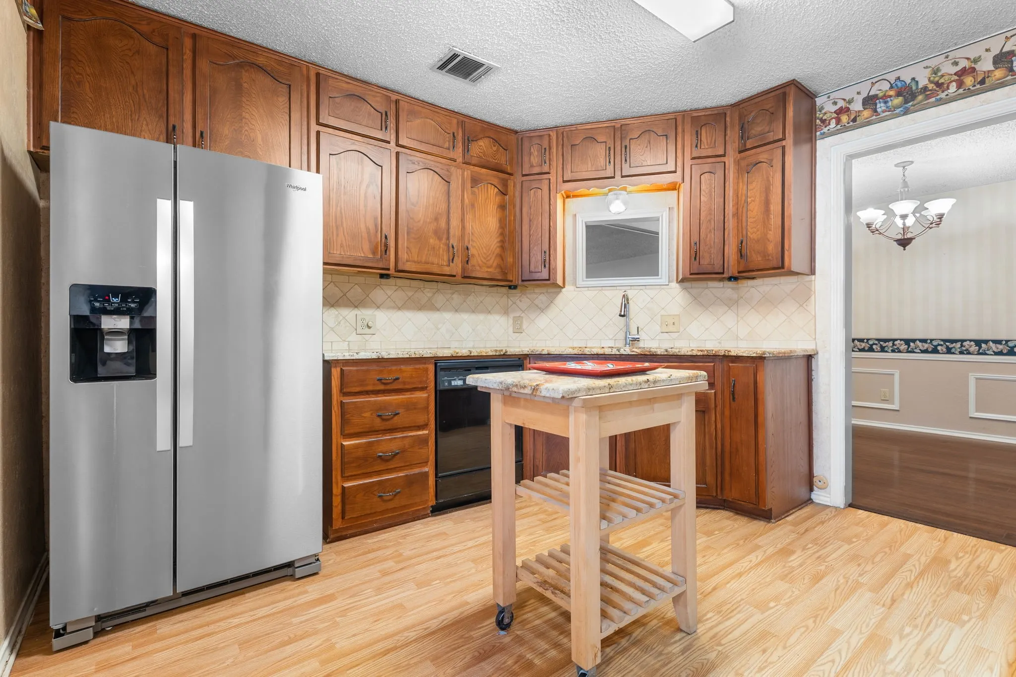 Wood-finish flooring with full-height cabinetry, solid surface countertops, and an undermount sink
