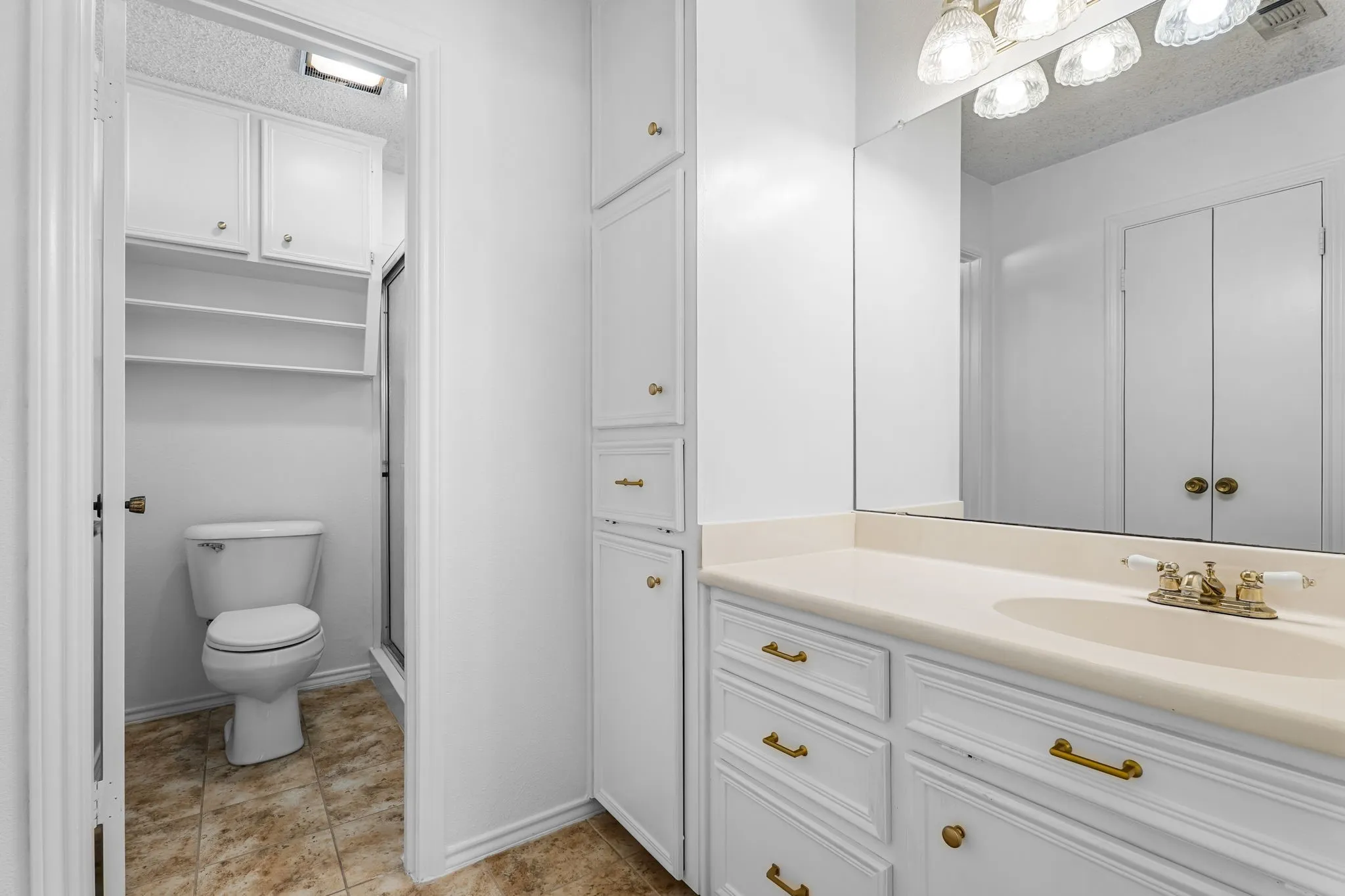 Bathroom with a single vanity, integrated sink, and gold-finish fixtures