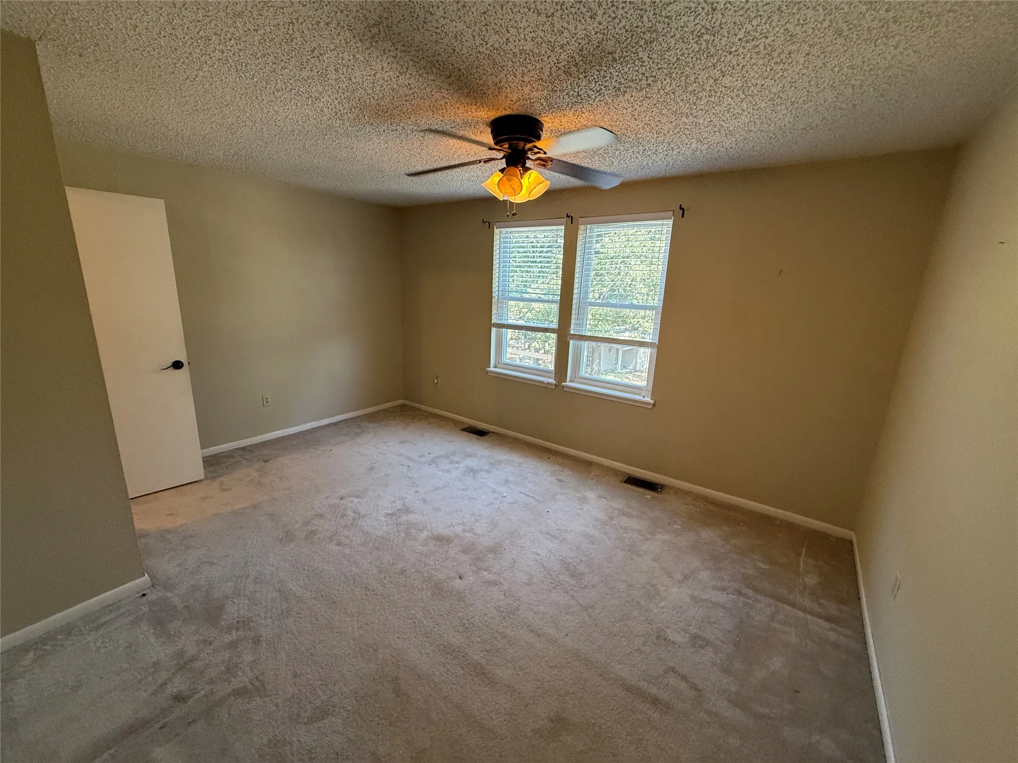 Room featuring a ceiling fan with integrated lighting, two windows, and a white interior door